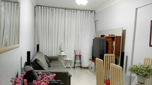 Una sala de estar con un sofá, una mesa de comedor de cristal y un mueble para televisión.