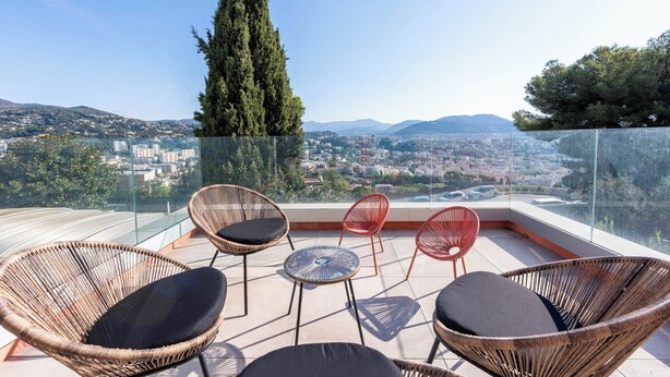 A balcony with wicker chairs and a small table, overlooking a cityscape with mountains in the distance. - Wonderful Villa, swimming pool and parking (Nice)