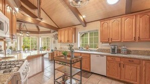 Una cocina amplia con armarios de madera, una isla central y un ventilador de techo.