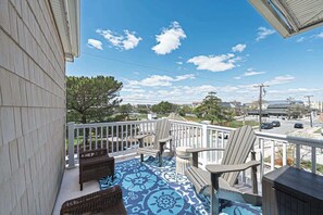 A balcony with a patterned floor, white railing, and wicker furniture. - Now avail Beach Block Getaway (Atlantic City)