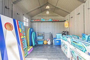 Una sala de deportes con mesa de ping pong, pelotas deportivas y varias bolsas.