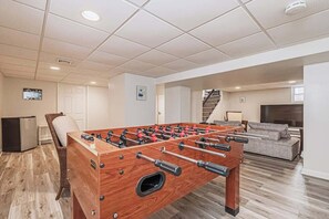 Una habitación con mesa de futbolín, televisor y sofá.