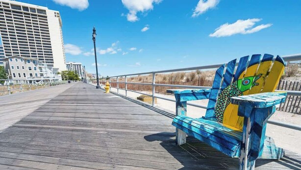 Une promenade en bois avec un banc orné d’un motif coloré représentant un poisson.