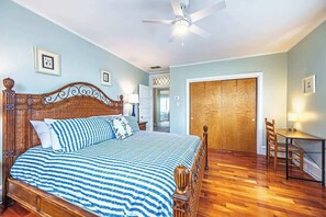 A bedroom with a bed, wooden headboard, ceiling fan, and a wooden door. - Now avail Beach Block Getaway (Atlantic City)