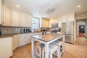 A kitchen with white cabinets, a wooden island, stainless steel appliances, and a tiled floor. - Now avail Beach Block Getaway (Atlantic City)
