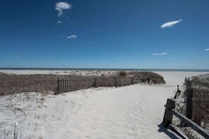 A sandy beach path with a wooden fence and sparse vegetation. - Now avail Beach Block Getaway (Atlantic City)