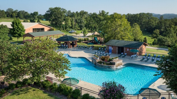 A swimming pool with lounge chairs and a gazebo, surrounded by greenery and a building with a sloped roof. -  Branson Woods 2 Bedrooms/2 Bathrooms Grand Villa (Branson)