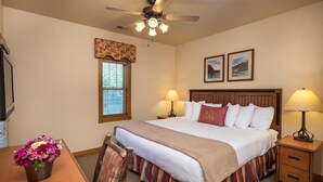 A hotel room with a bed, two bedside tables with lamps, a window with blinds, a ceiling fan, and a small table with a flower arrangement. -  Branson Woods 2 Bedrooms/2 Bathrooms Grand Villa (Branson)