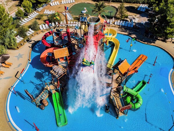 A water park with multiple slides and water features, surrounded by sun loungers and a pool. - Amadria Exclusive Beach Villa (Sibenik)