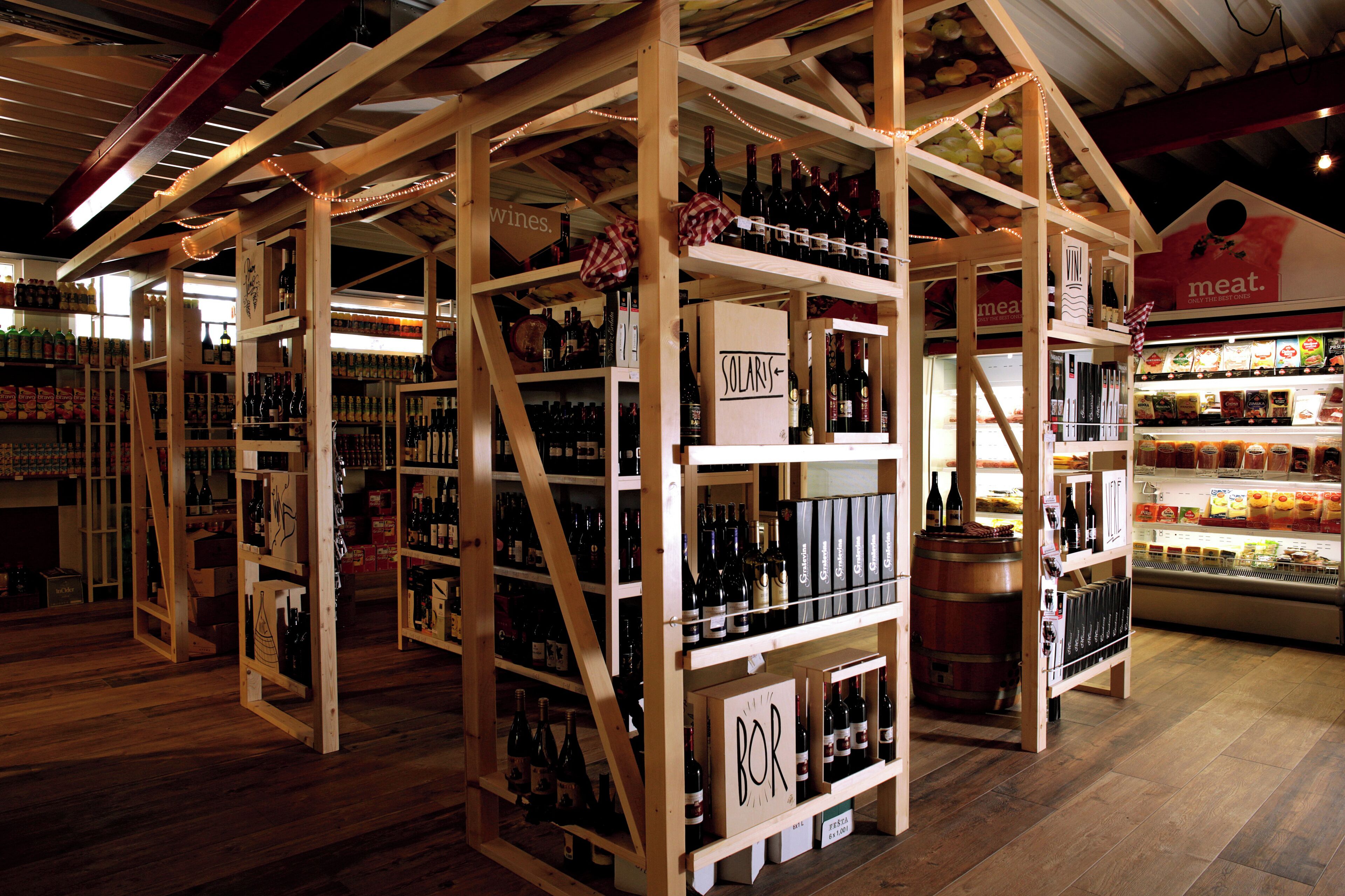 Una tienda de vinos con estantes de madera y una sección de carnes.