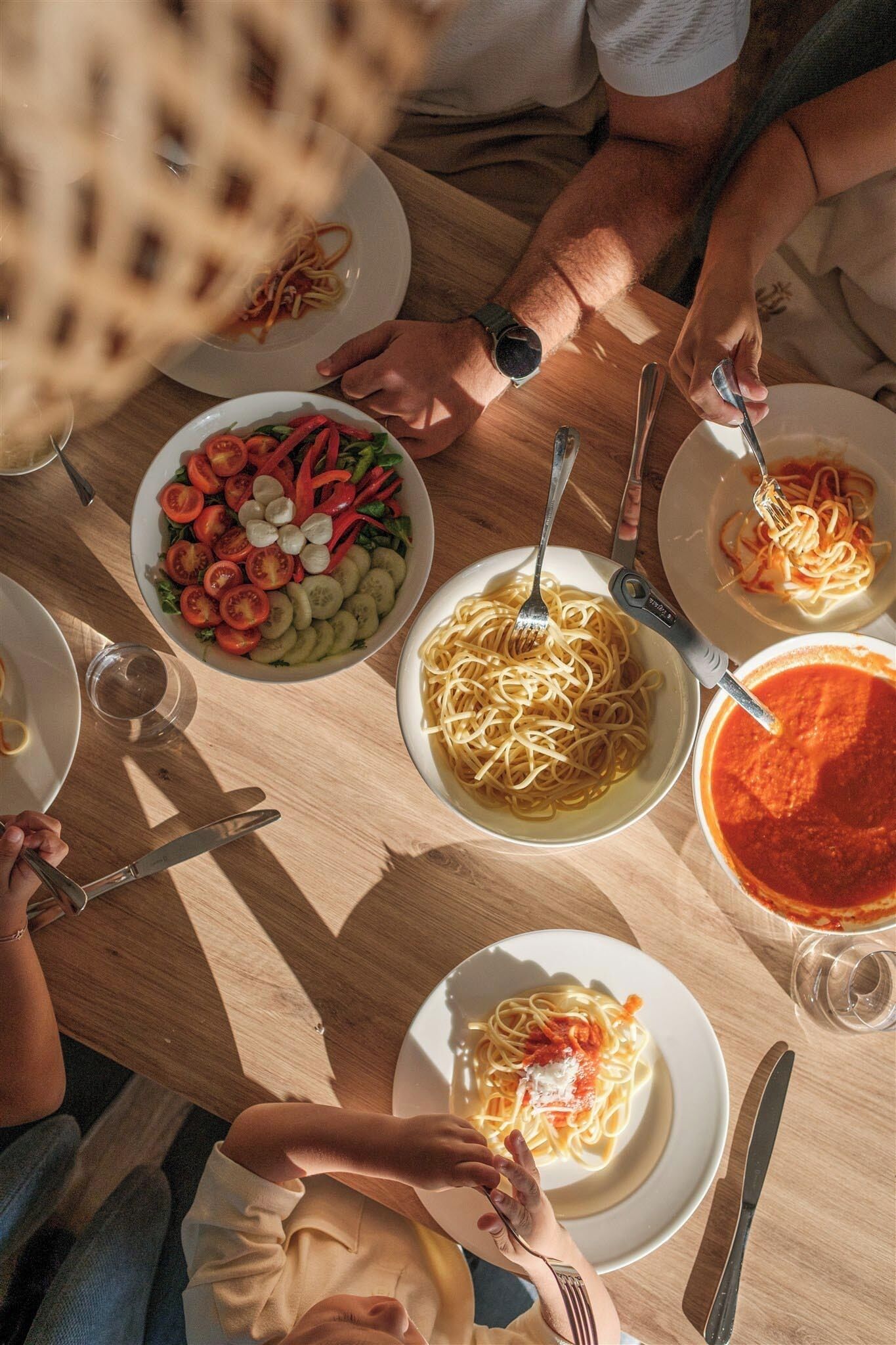 A dining table with multiple plates of food, including pasta and a salad.