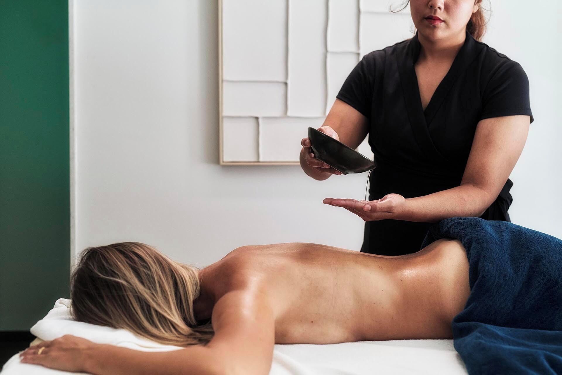 En person ligger på en massageloung og modtager en behandling.