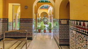 A corridor with tiled walls and arches, leading to a courtyard with potted plants. - Cathedral PentHouse (Sevilla)