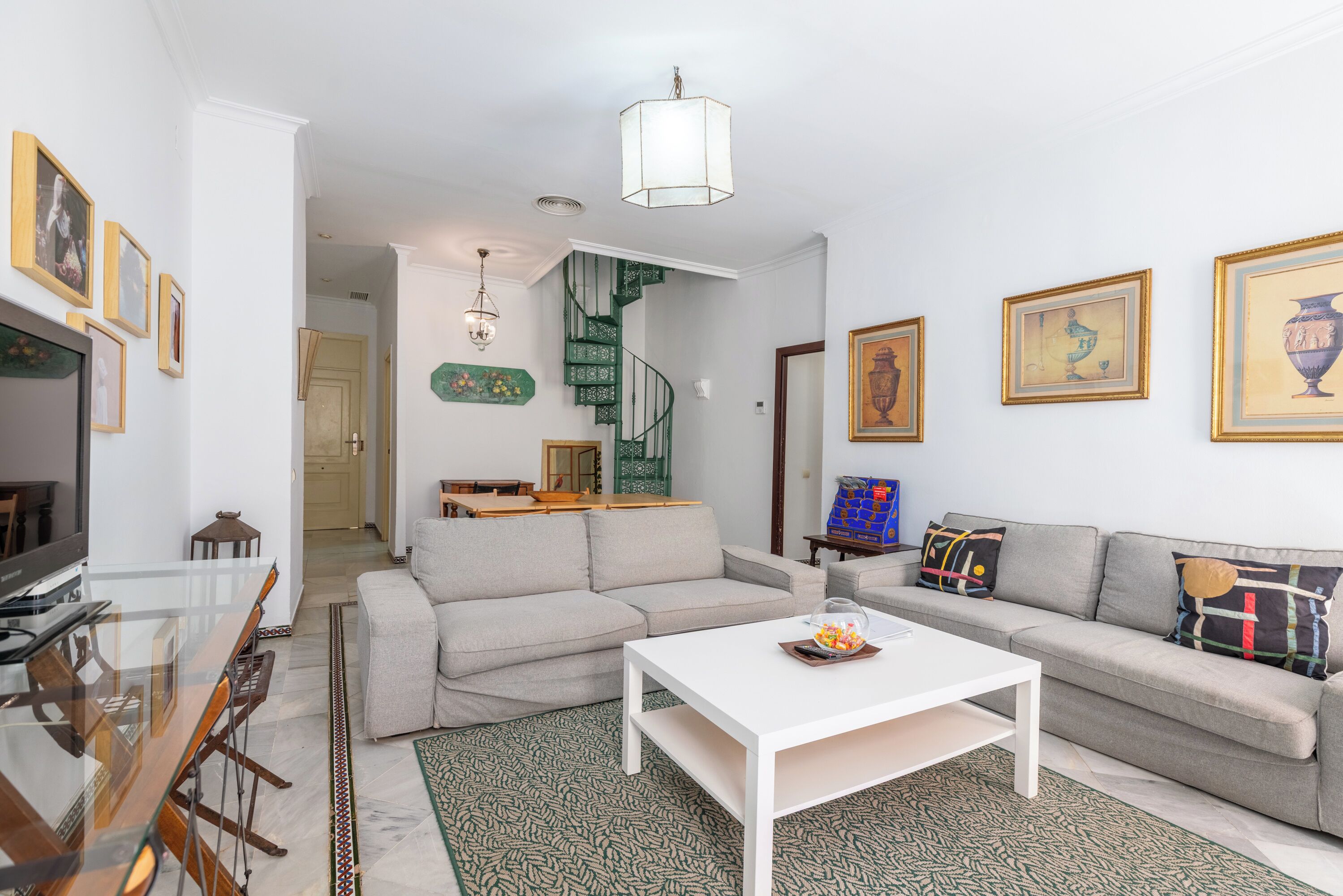 Ein Wohnzimmer mit einer Couch, einem Couchtisch, einem Fernseher und einer Treppe.