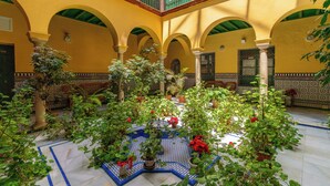 A courtyard with arches, potted plants, and a tiled floor. - Cathedral PentHouse (Sevilla)