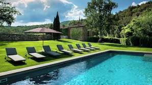 A swimming pool with lounge chairs and a stone wall.