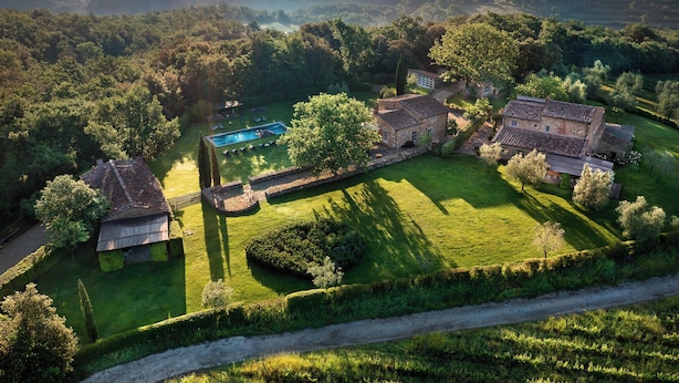 A large estate with multiple buildings, a swimming pool, and expansive green lawns.
