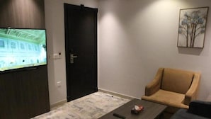 Un salon doté d’un téléviseur à écran plat, d’un canapé de couleur sombre, d’une table basse en bois et d’un tapis à motifs.