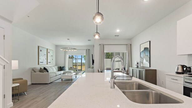 A modern kitchen with a large island, stainless steel appliances, and a view to the outdoors.