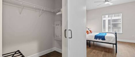 A bedroom with a bed, a ceiling fan, a window with blinds, and a white door.