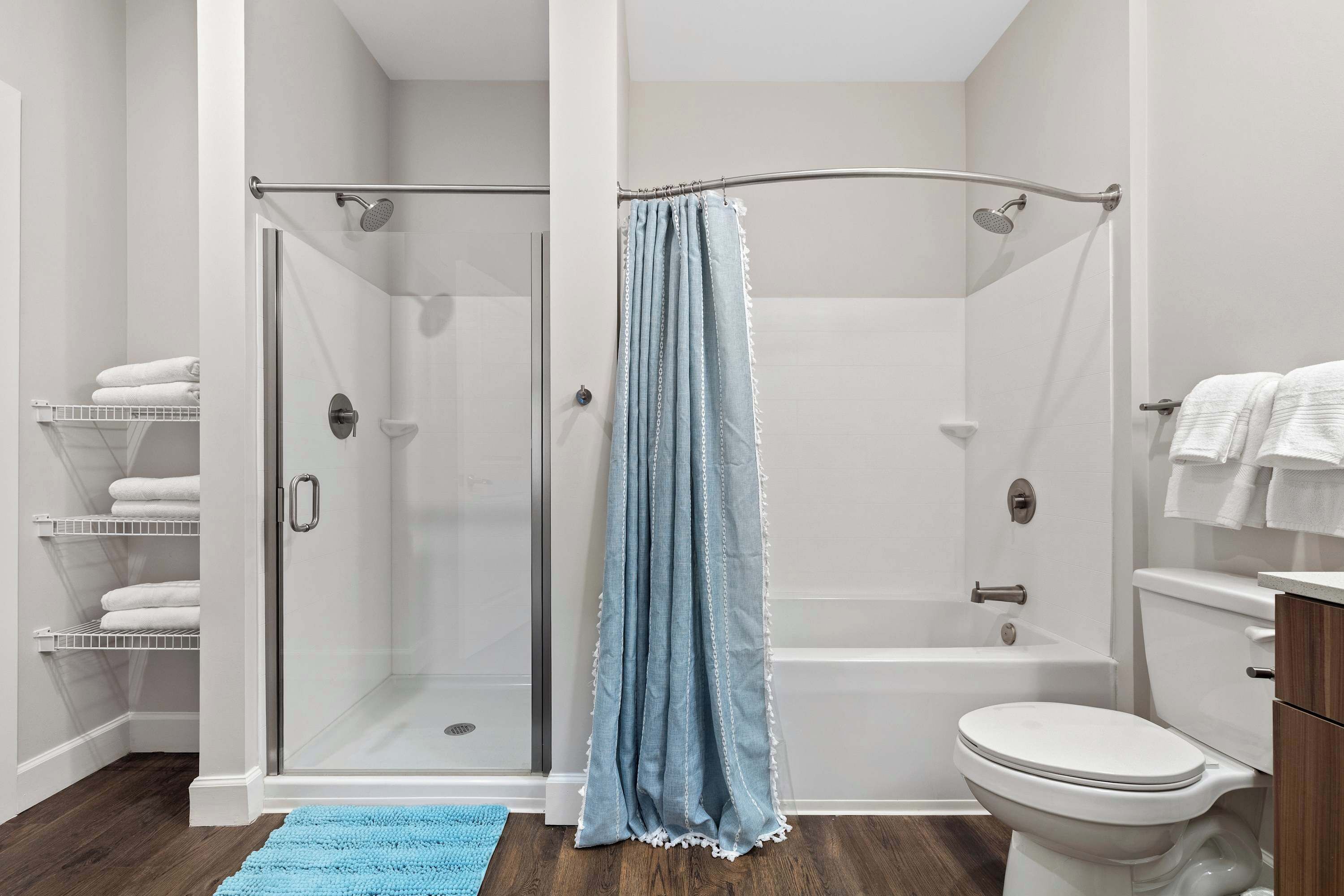 Une salle de bain avec une douche à parois de verre, une baignoire, des toilettes et un porte-serviettes avec des serviettes.