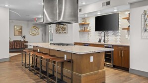 Una cocina moderna con una isla central, taburetes de bar, una campana extractora de acero inoxidable y un lavavajillas empotrado.