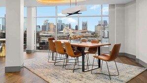Un moderno comedor con una gran mesa, sillas y vistas de la ciudad a través de amplios ventanales.