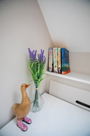 A bookshelf with books and a vase with flowers.