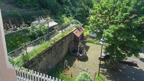 A view of a garden with a stone wall, a small building, and a car parked nearby. - Spacious vacation apartment in Falkenstein - in the middle of the Donnersbergkreis hiking region (Falkenstein)