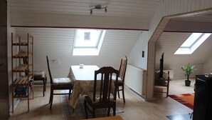 A dining area with a table and chairs, a wooden bookshelf, and a potted plant. - Spacious vacation apartment in Falkenstein - in the middle of the Donnersbergkreis hiking region (Falkenstein)