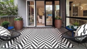 A modern outdoor area with a patterned rug, two chairs, and a glass door leading to an interior space. - Point Grey Newly Constructed Estate (Vancouver)