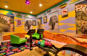 A room with colorful walls, a green sofa, exercise balls, and a wooden bench.