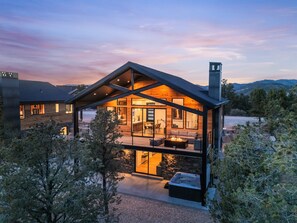 A modern house with a large deck, a hot tub, and a fireplace.