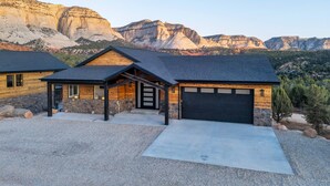 A modern house with a garage, a covered porch, and a driveway. - High Desert Home | Modern Luxury Near Zion NP (Orderville)