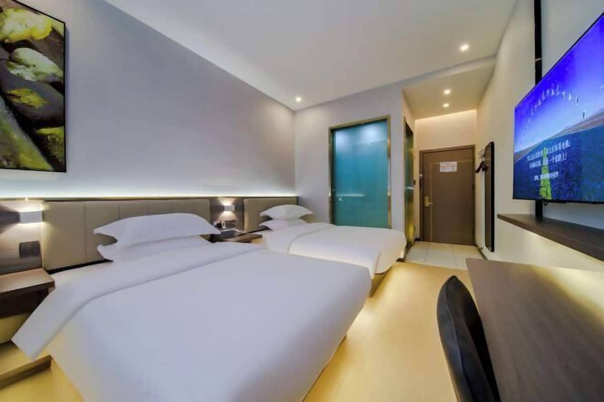 A hotel room with two beds, a flat-screen TV, and a painting on the wall.