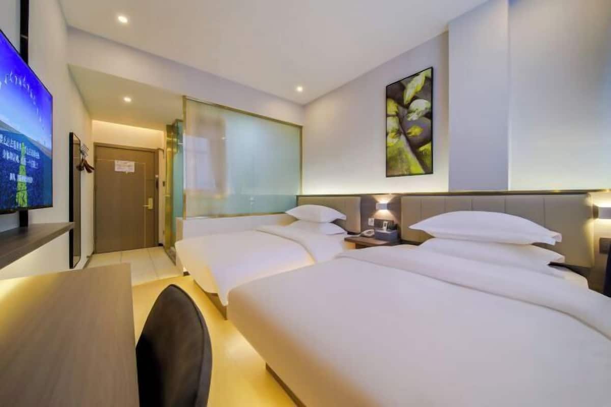 A hotel room with two beds, a desk, a TV, and a painting on the wall.