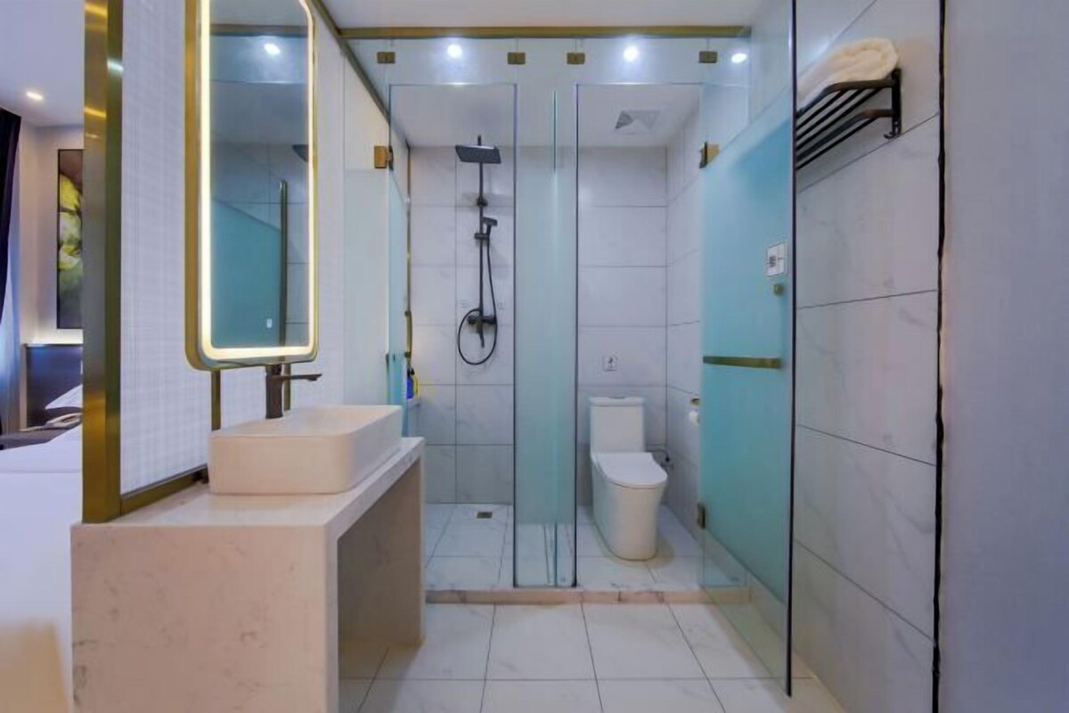 A modern bathroom with a glass shower enclosure, a white toilet, and a vanity with a mirror.