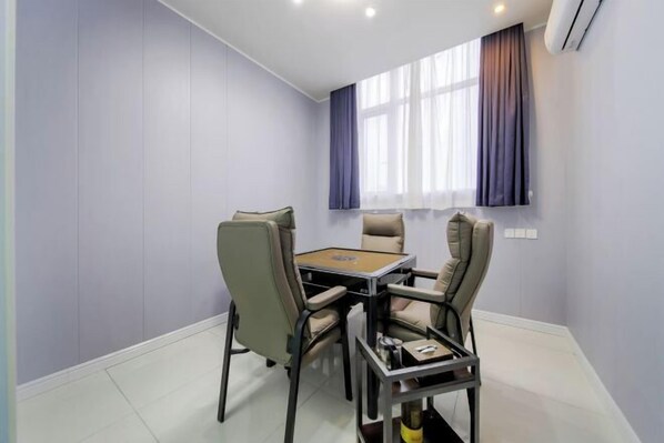 A room with a round table and four chairs, a window with curtains, and an air conditioning unit on the wall. - 7Days Inn Hotel (Zhoukou Wuyi Square City Central Hospital) (Zhoukou)