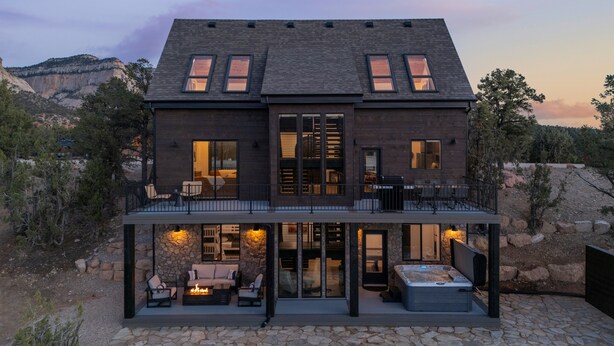 A modern two-story house with a stone patio, outdoor seating, and a hot tub. - Sunset Pointe| Modern Comfort| Epic Views| Zion (Orderville)