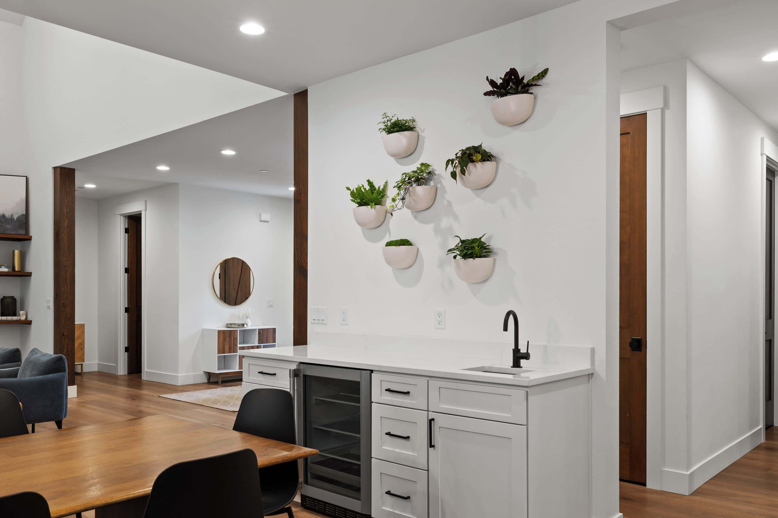 A modern kitchen with white cabinets, a wooden dining table, and recessed ceiling lights.