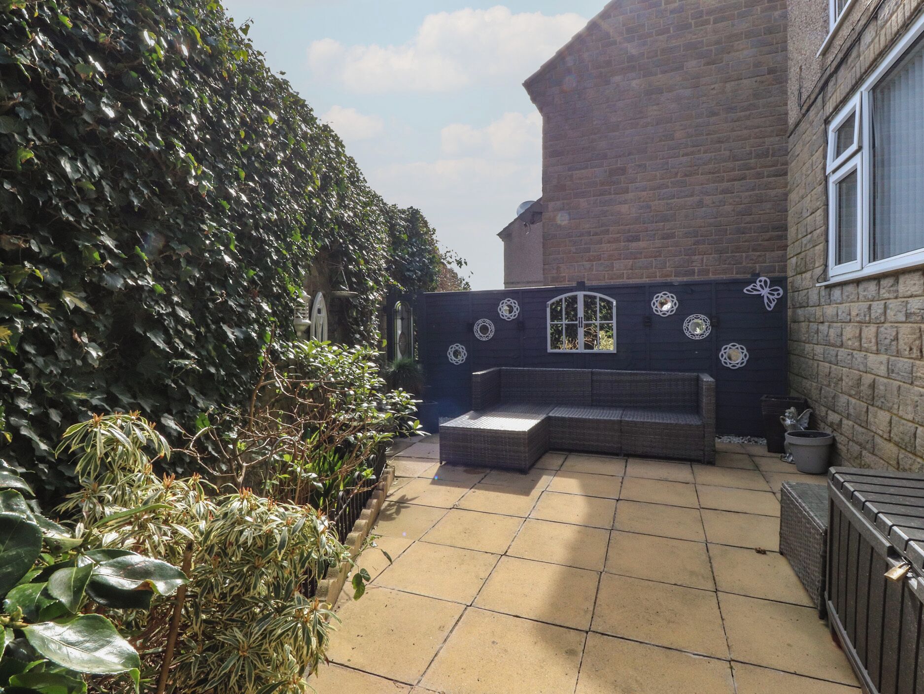 A patio area with a bench, a tiled floor, and a brick wall with decorative elements.