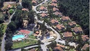 An aerial view of a residential area with houses arranged in a curved layout, a swimming pool, and a road running through the center. - Quiet 3*** listed vacation home with swimming pool (Saint-Julien-en-Born)