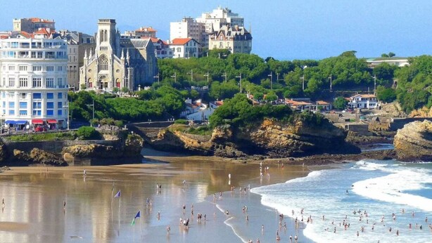 A beach with people swimming and walking along the shore, buildings in the background, and a rocky coastline. - Quiet 3*** listed vacation home with swimming pool (Saint-Julien-en-Born)