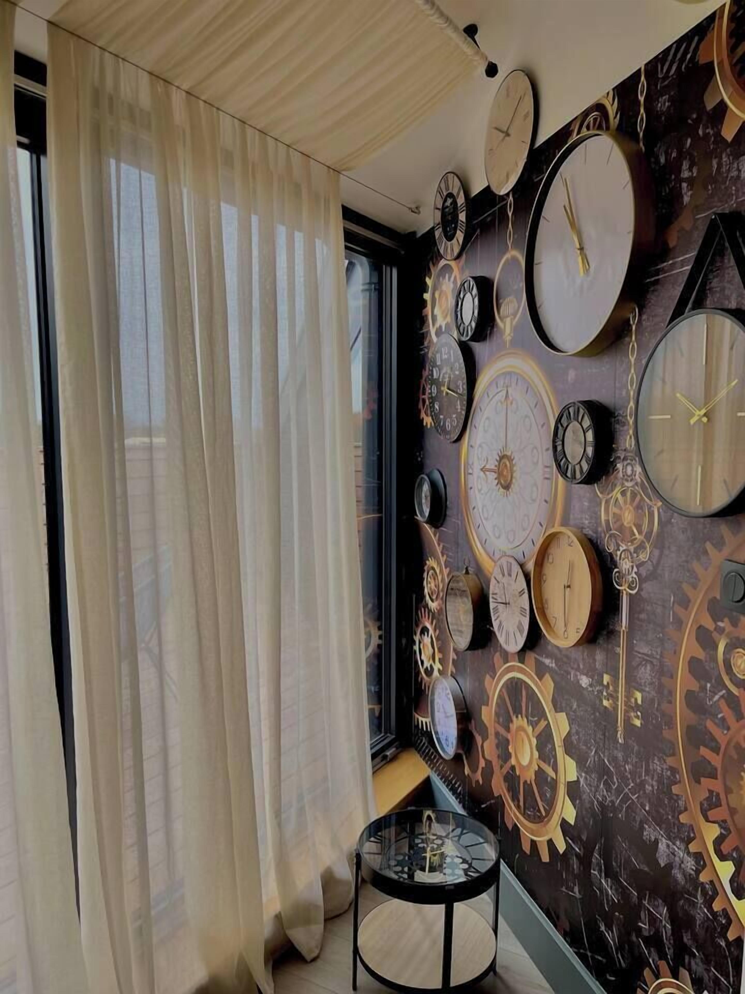 Een kamer met een groot raam, dunne gordijnen en een muur versierd met verschillende klokken en tandwielen.