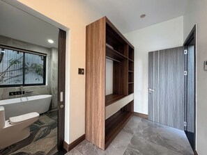 A modern bathroom with a freestanding bathtub, a toilet, and a window with a view of trees. - Maya Villa Da Nang (Da Nang)