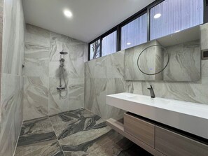 A modern bathroom with a shower, a vanity with a mirror, and marble tiles. - Maya Villa Da Nang (Da Nang)