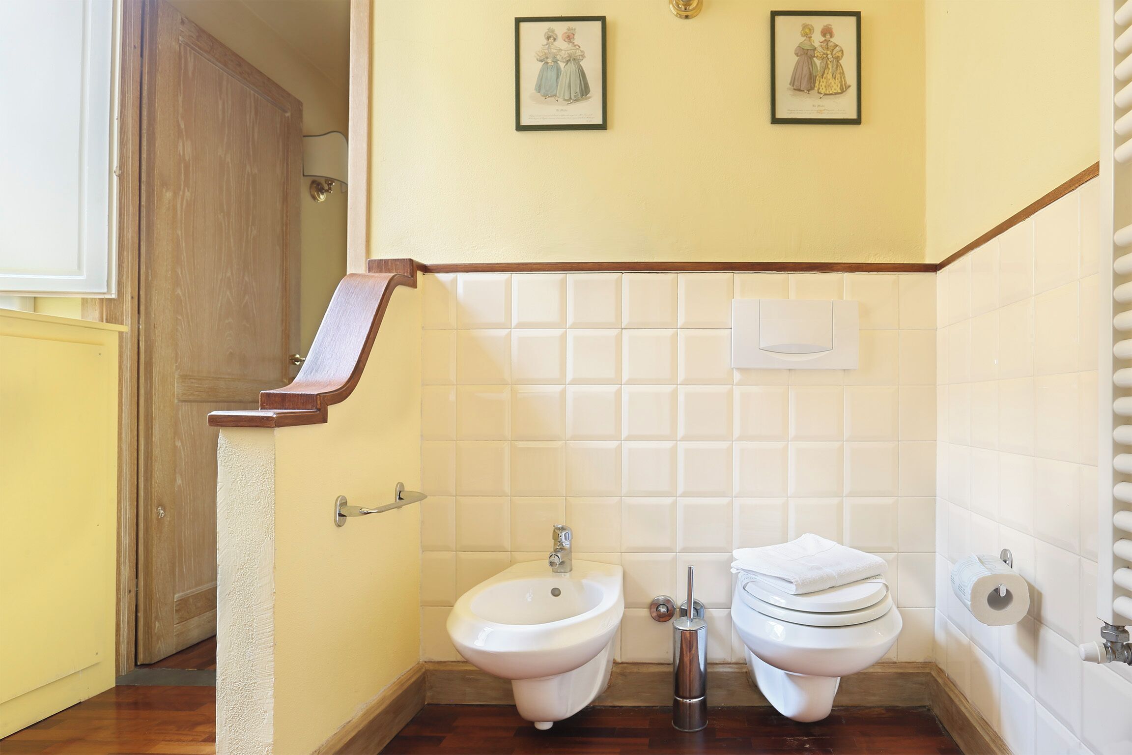 Un baño con bidé, inodoro y perchero.