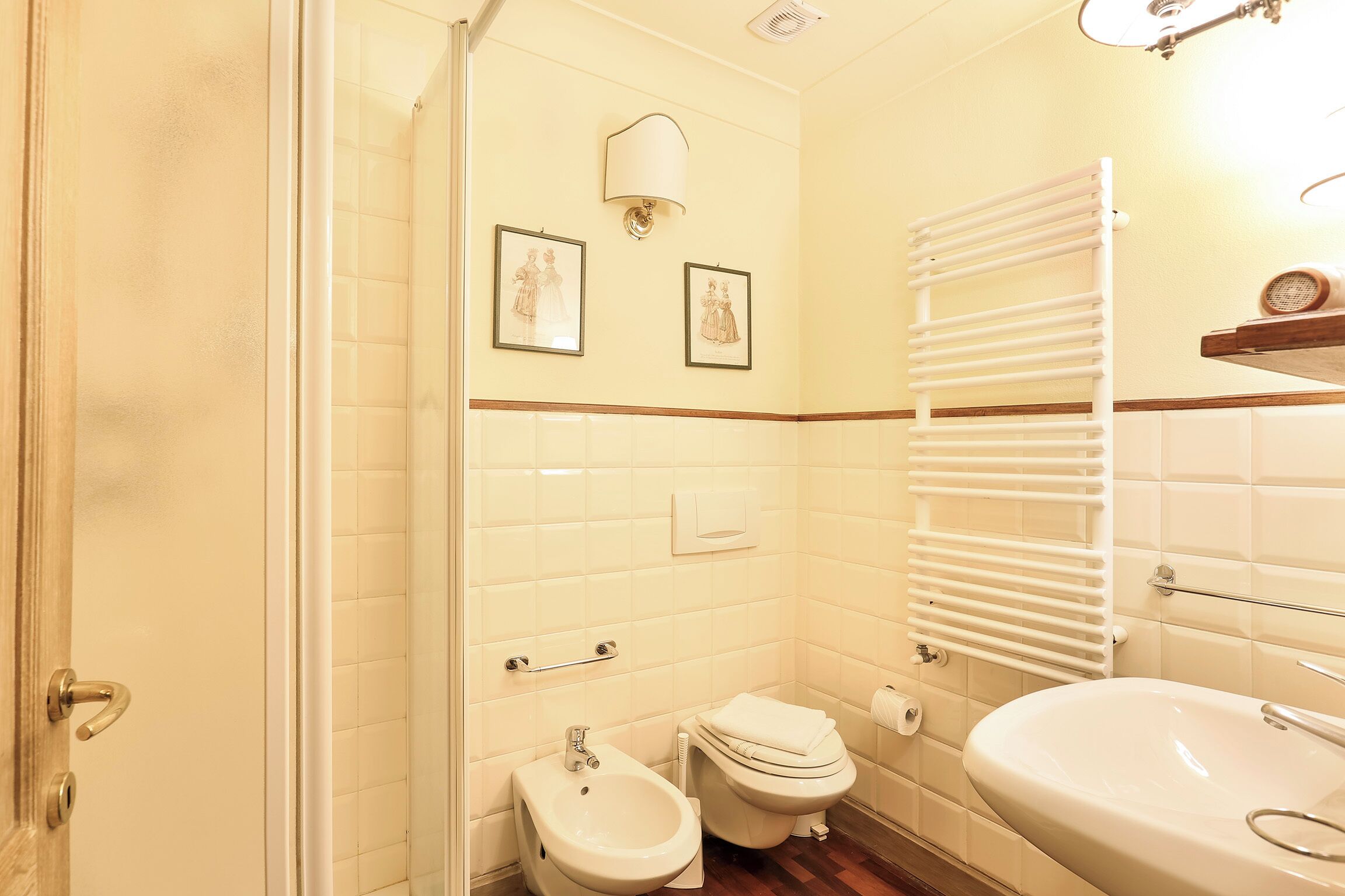 A bathroom with a toilet, bidet, sink, and a towel rack.