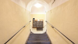 A staircase with metal handrails, a light fixture at the top, and a storage unit with drawers against the wall.