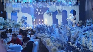 A decorated event space with a stage, floral arrangements, and seating for guests. - Xinxiang Jinghua Tropical Mineral Spring Health Garden (Xinxiang County)